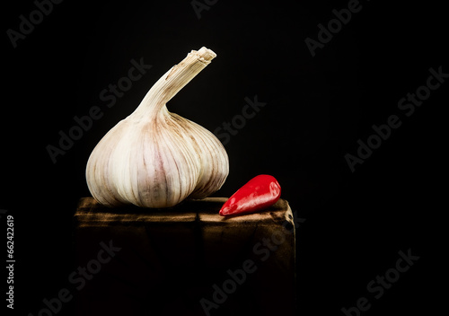 Head of garlic with red pepper on a dark background.