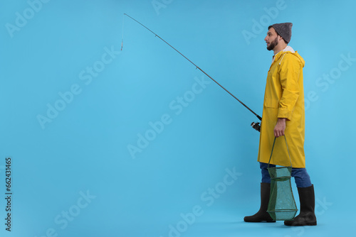 Fisherman with rod and fishing net on light blue background, space for text