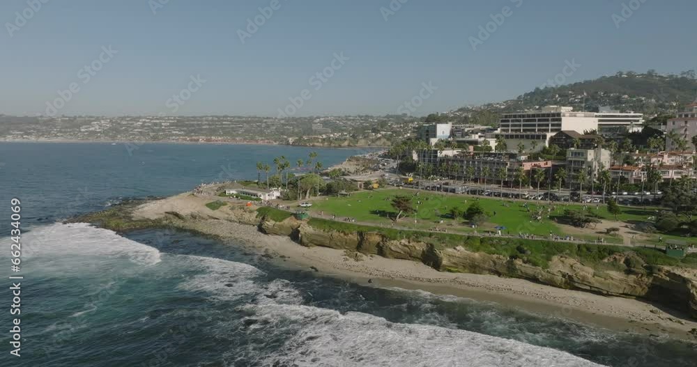 A stunning beach scene with a body of water, city buildings, and waves crashing against the shore. A stunning beach scene with a body of water, city buildings, and waves crashing against the shore.