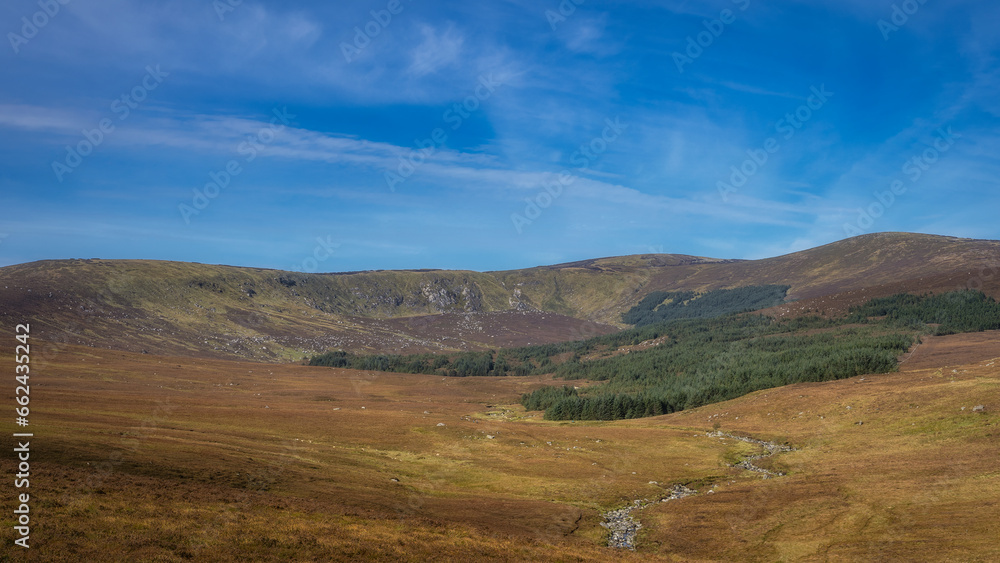 Beautiful vista with stream leading to the forest and Lough Ouler that hiding behind it. Foothill of Tonelagee Mountain, Wicklow Mountains, Ireland Beautiful vista with stream leading to the forest and Lough Ouler that hiding behind it. Foothill of Tonelagee Mountain, Wicklow Mountains, Ireland