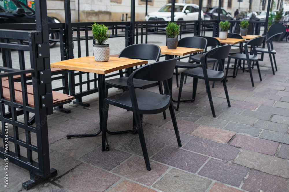 Modern street cafe with wooden tables with chairs standing next to them. Architecture and landmarks of Krakow. High quality photo