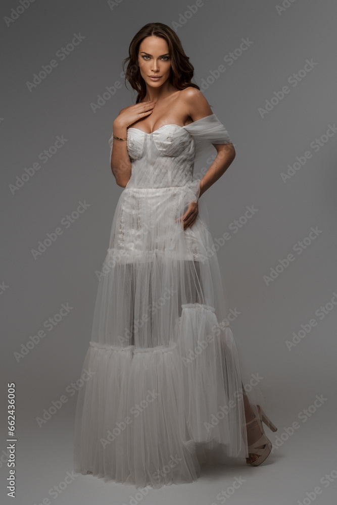 Beautiful model in resplendent white dress amidst Greek art sculptures in studio ambiance Beautiful model in resplendent white dress amidst Greek art sculptures in studio ambiance