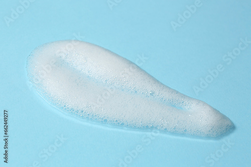 Foam on light blue background. Face cleanser, skin care cosmetic