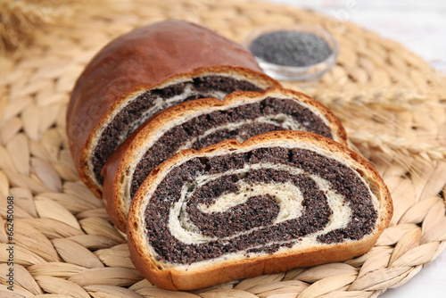 Foto Cut poppy seed roll on wicker mat, closeup. Tasty cake