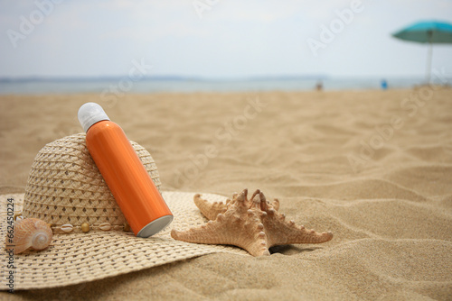 Sunscreen, hat and starfish on sand, space for text. Sun protection care