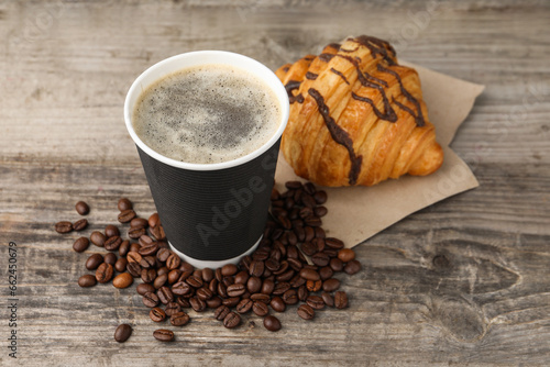 Fototapeta Naklejka Na Ścianę i Meble -  Coffee to go. Paper cup with tasty drink, beans and croissant on wooden table