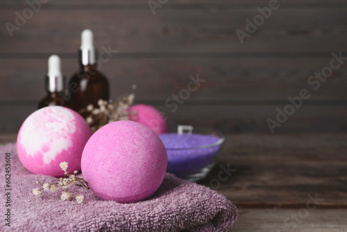 Beautiful aromatic bath bombs  gypsophila flowers and soft towel on table  closeup. Space for text