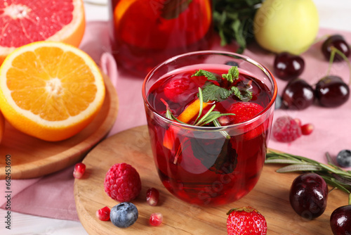 Glass of delicious sangria, fruits and berries on table, closeup