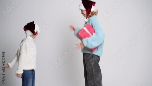 Little boy and girl with present in santa claus cap. Concept Christmas and New Year