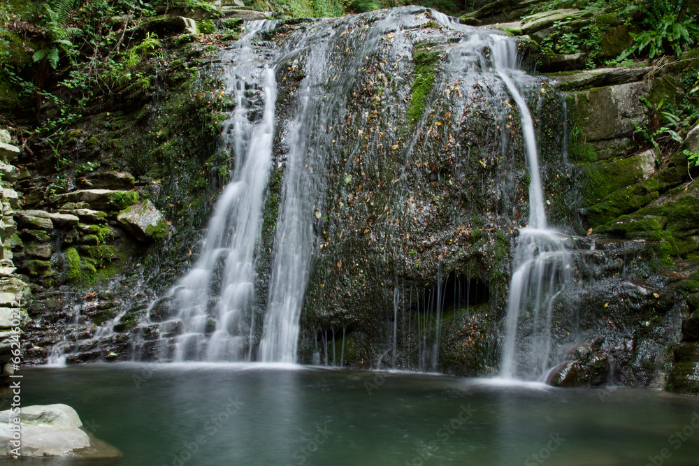 Silk effect of famous waterfall near Como city hidden by vegetation