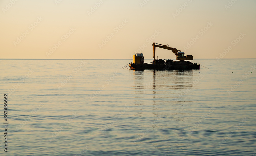 Machinery and ship in the sea for Breakwater construction at sunrise. Marine industry .