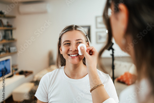 Makeup process. Professional artist applying make up on model face. Close up portrait of beautiful blonde woman in beauty salon.