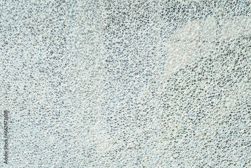 Broken reinforced, hardened or laminated glass to little pieces like mosaic. Cracked glass on white background. High resolution abstract texture
