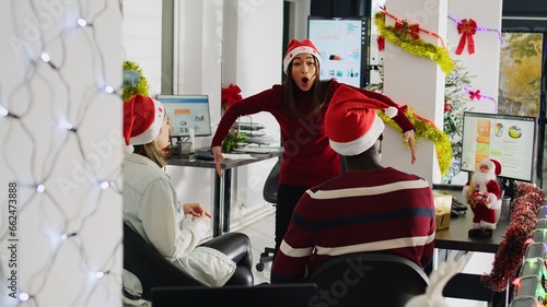 Obraz na płótnie Diverse workers wearing Santa hat enjoying Christmas spirit mood playing pretending acting game during break
