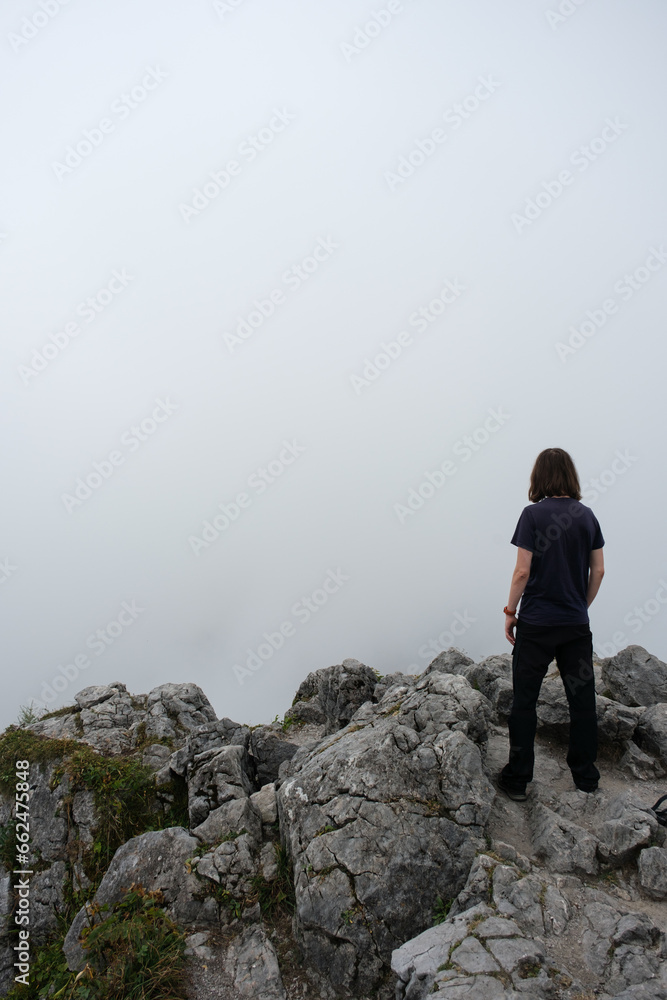 Einsamer Wanderer mit Blick nach unten auf Berggipfel bei Nebel