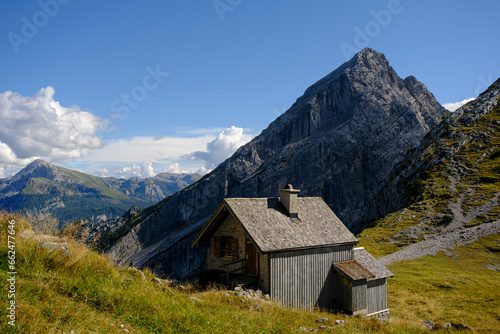 Hangkante auf Hochebene mit Bergspitze im Hintergrund und naher Hütte im Vordergrund photo