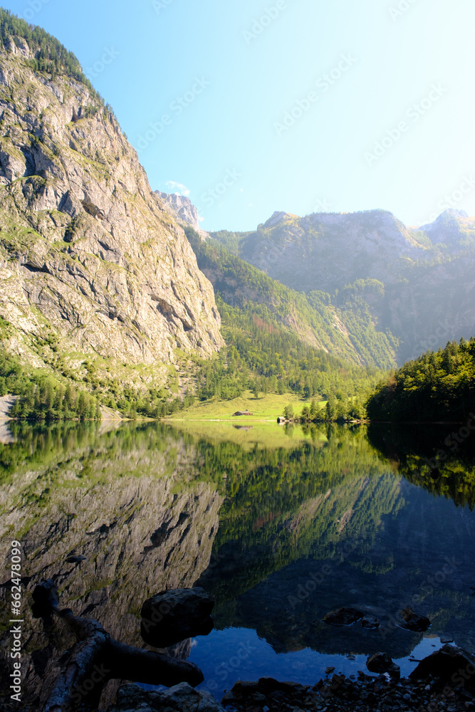 Almhütte am spiegelndem Bergsee im Sommer bei Sonnenschein Almhütte am spiegelndem Bergsee im Sommer bei Sonnenschein