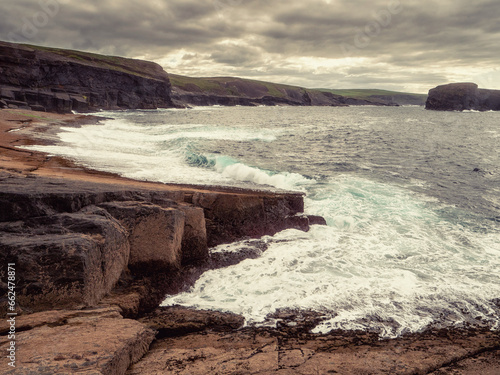 Rough stone coast with cliffs and ocean scene. Ireland, Kilkee area. Travel, tourism and sightseeing concept. Irish landscape and coastline nature view. Dark and moody feel. photo