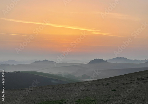 Sunrise in the rolling hills of Tuscany, with some fox on the background