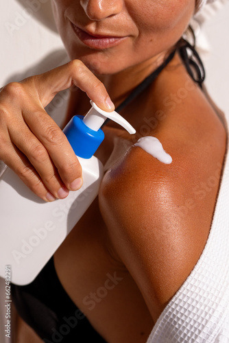 with the procedure of applying moisturizer to a woman's shoulder © sutulastock