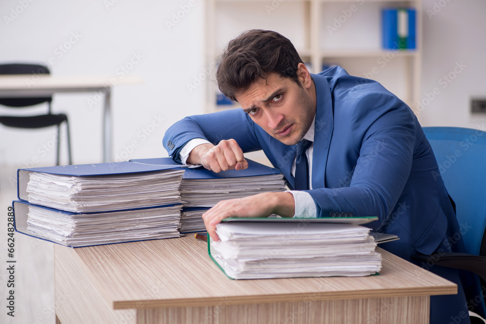 Young male employee and too much work in the office Young male employee and too much work in the office