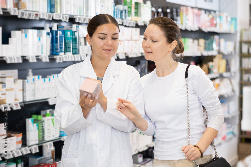 Woman pharmacist gives advice to woman customer what cosmetic product to buy in pharmacy