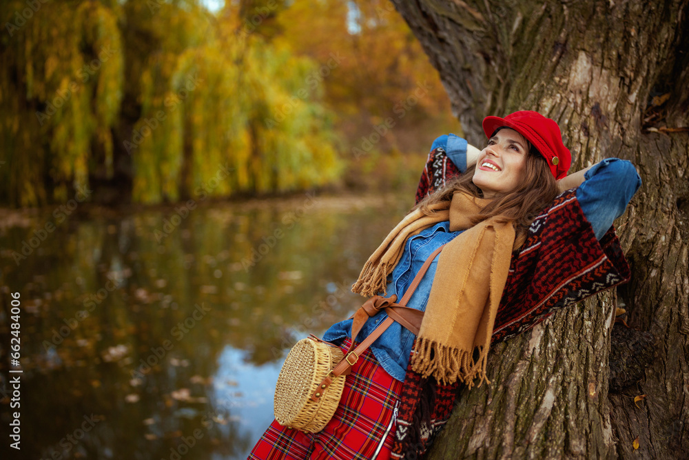 relaxed modern woman in jeans shirt and red hat with scarf