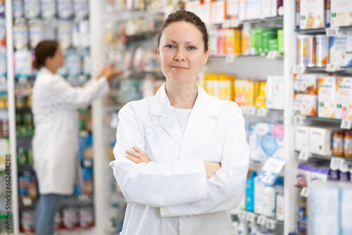 Adult female pharmacist in medical uniform posing while working in pharmacy