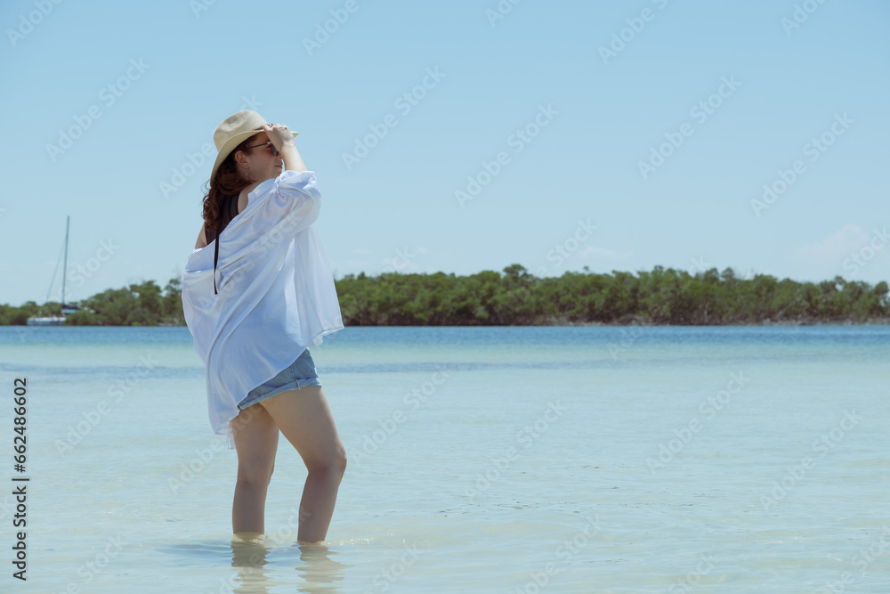 unrecognizable white woman with feet in the sea looking at the horizon