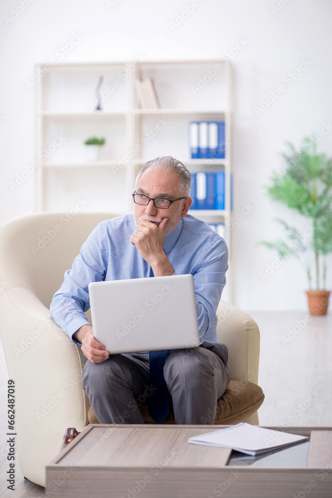 Old male employee sitting on arm-chair Old male employee sitting on arm-chair