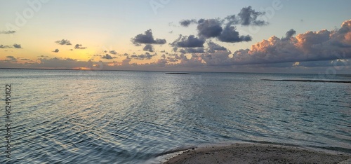 Tranquil Sunset Over Gentle Ocean Waves with large, puffy clouds