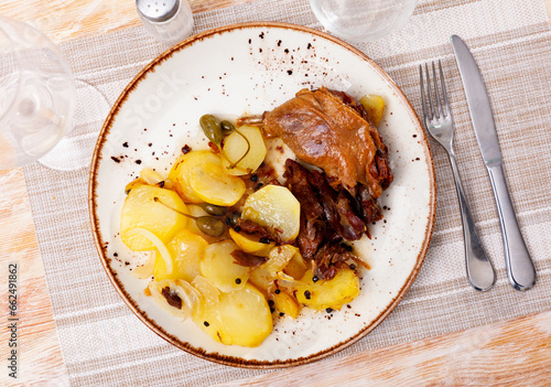 French cuisine, fried duck confit with roasted potatoes on a plate in a restaurant photo