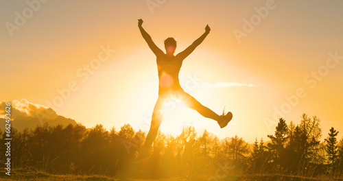 SILHOUETTE, LENS FLARE: Sporty woman jumps with joy as she runs to top with dog