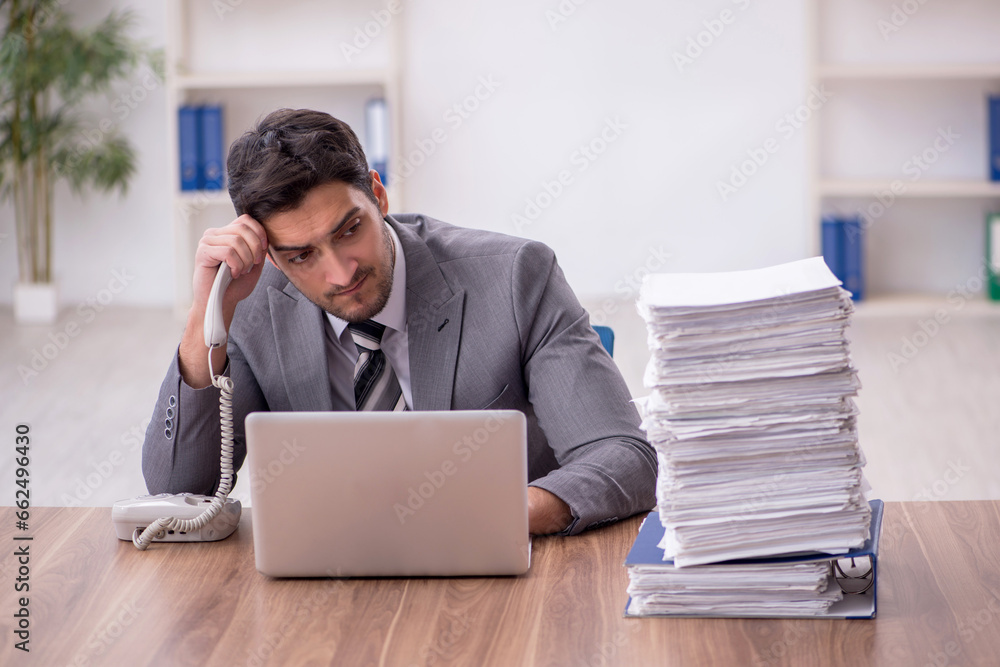 Young male employee and too much work in the office Young male employee and too much work in the office