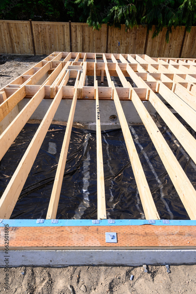 Beginnings of a new home, wood floor joists installed over concrete