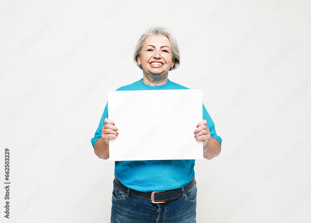 Portrait of happy senior woman wearing blue tshirt with blank advertising board or copy space Portrait of happy senior woman wearing blue tshirt with blank advertising board or copy space