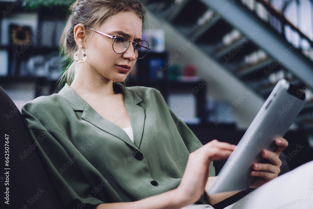Confused woman using and focusing on tablet Confused woman using and focusing on tablet