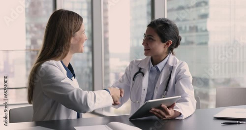 Wallpaper Mural Two young multiethnic women, medical workers, colleagues accomplish formal meeting in clinic office successfully shake hands express respect and gratitude for effective cooperation. Teamwork, medicine Torontodigital.ca