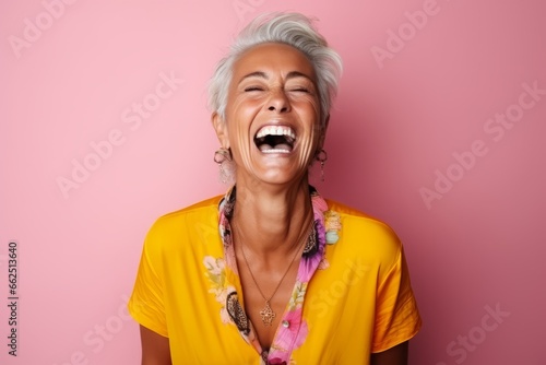 Portrait of a happy senior woman laughing against pink background. Copy space.