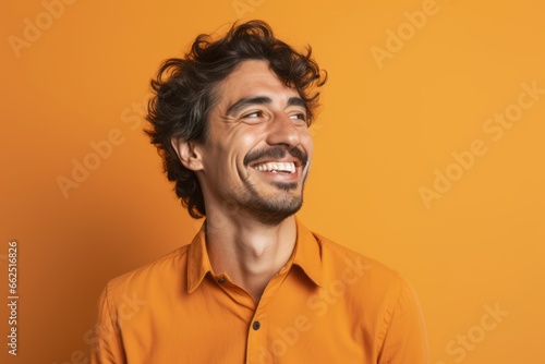 Portrait of a happy young man laughing, isolated over orange background