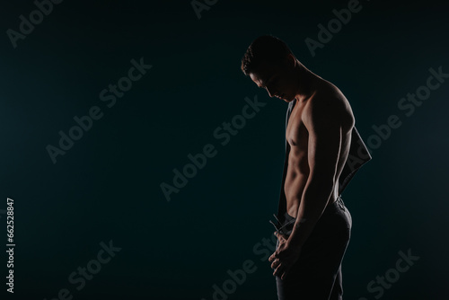 Muscular man, fit model, shows strong physique. Inspiring silhouette, healthy, active lifestyle. Sculpted chest, abs, arms. Athlete, sportsman. Studio pose.