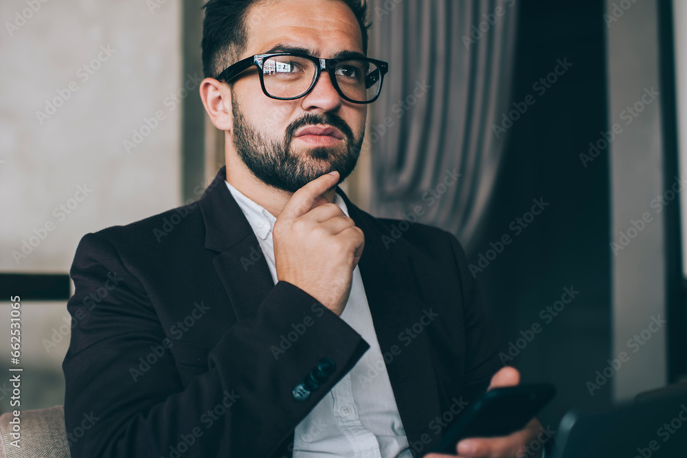 Pensive ethnic boss watching phone at workplace Pensive ethnic boss watching phone at workplace