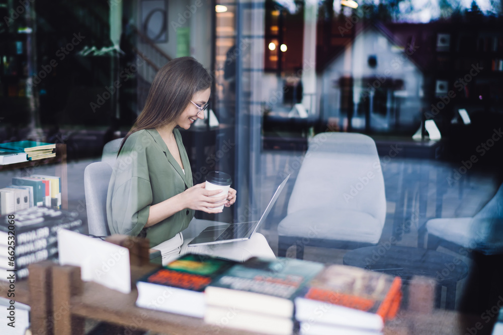 Young smart lady using laptop in bookstore Young smart lady using laptop in bookstore
