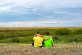 Two children sitting in the steppe with their backs. High quality photo