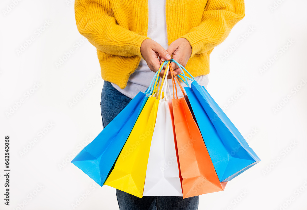 Happy woman hand she wears yellow shirt holding shopping bags multicolor, young female hold many packets within arms isolated on white background, Black Friday sale concept Happy woman hand she wears yellow shirt holding shopping bags multicolor, young female hold many packets within arms isolated on white background, Black Friday sale concept