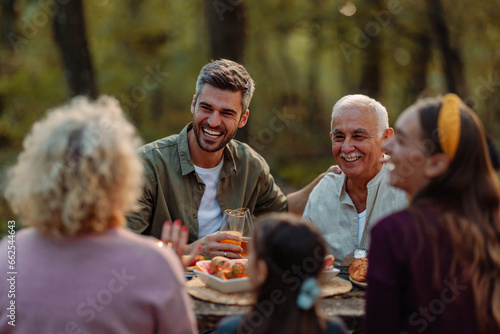 Father and grandfather laughing during a family picnic in forest