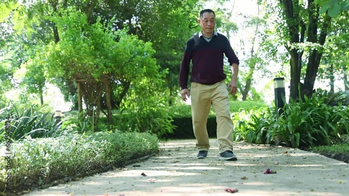 Elderly asian man walks with knee pain in his left knee tendonitis chronic muscle pain suffering and physical deterioration due to old age standing relieve pain with massage therapy. photo