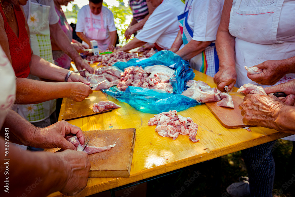 Elderly man and several women are cutting are cutting meat