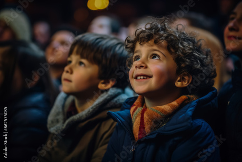 A wide-eyed little boy gazes with wonder at the stage during his first theater visit 