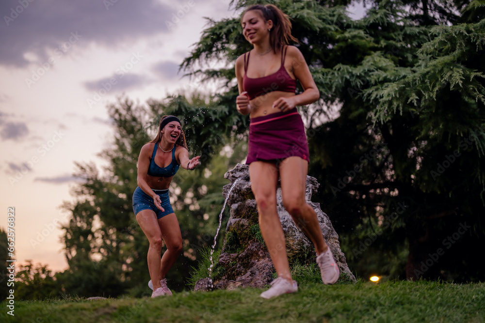 Fit girls having fun, splashing water in a park. Active and attractive athletes, with athletic bodies. Happy and healthy, enjoying outdoor sport and exercise. Fit girls having fun, splashing water in a park. Active and attractive athletes, with athletic bodies. Happy and healthy, enjoying outdoor sport and exercise.